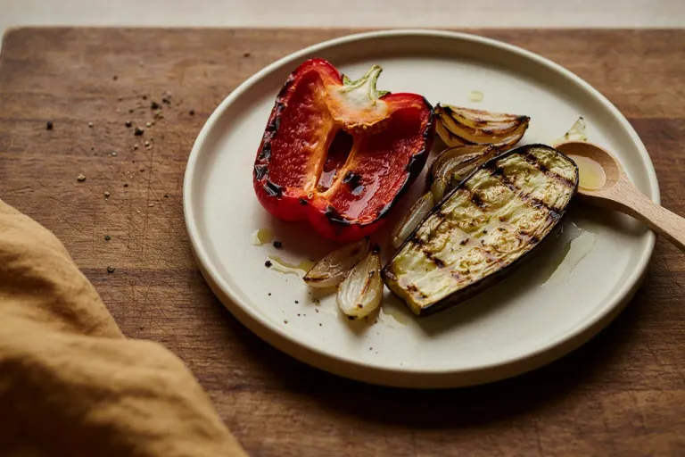 Grilled vegetables and peppers with charred skins on a plate