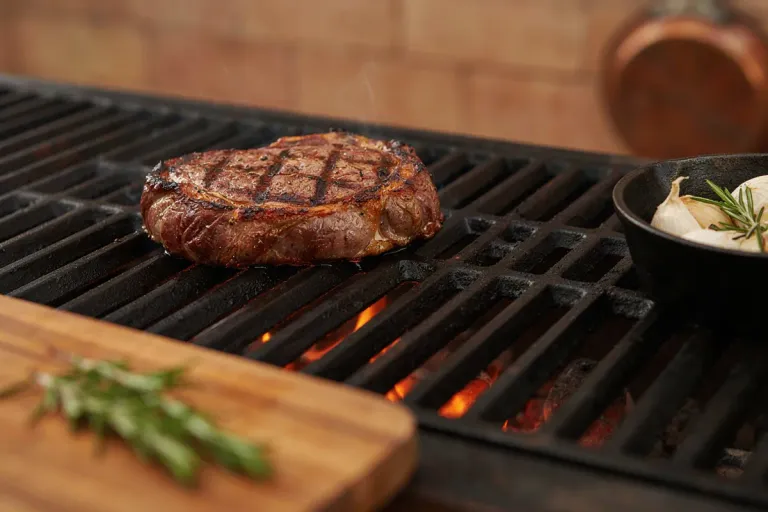 A thick steak on a charcoal grill with a wooden board in front